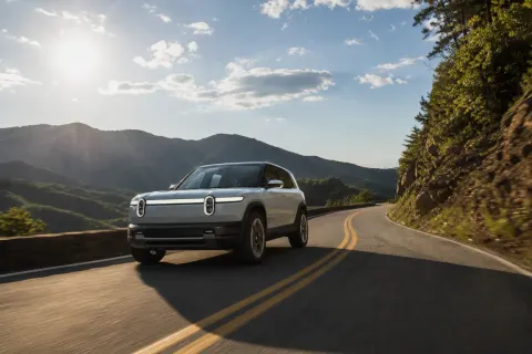 A Rivian R2 crossover accelerating on a sunny highway