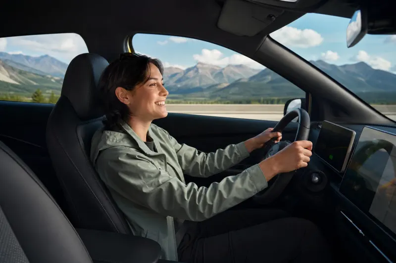 A scenic view from inside an electric vehicle showing the road ahead with mountains in the background.