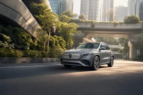 A mid-drive shot of the new Mercedes GLA electric SUV on a tech-inspired urban street