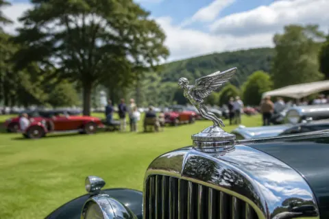 A classic car with an intricate hood ornament gleaming in the sunlight.