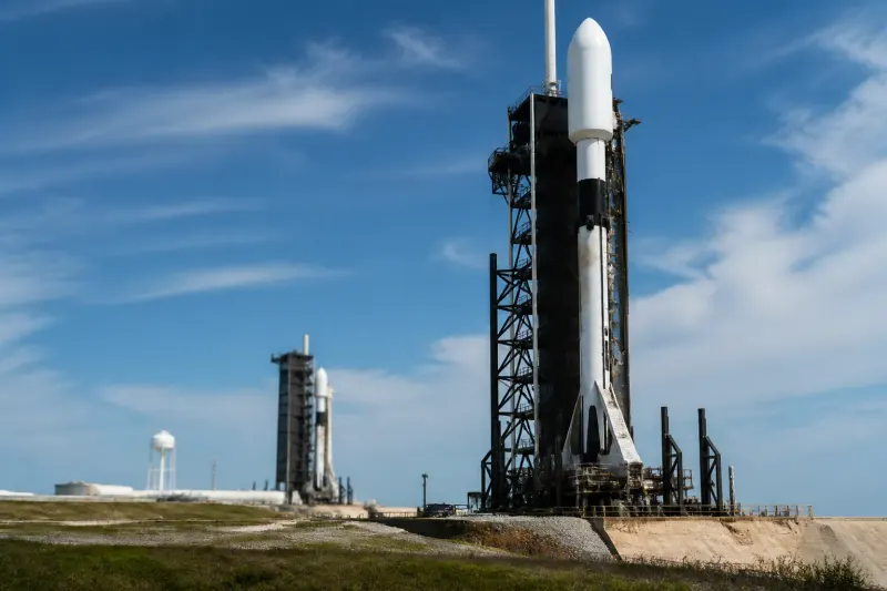A SpaceX launch pad with various rockets displayed against the sky.