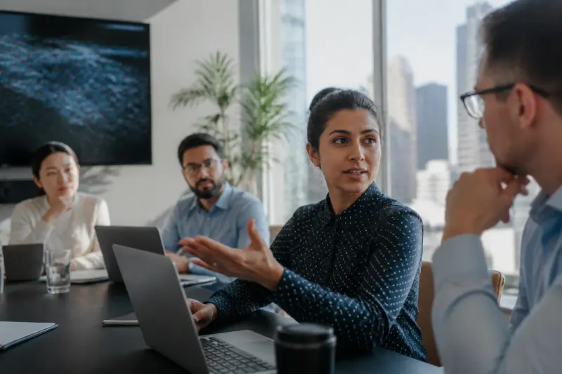A cybersecurity expert discussing the impact of banking trojans with colleagues in a bright office setting.