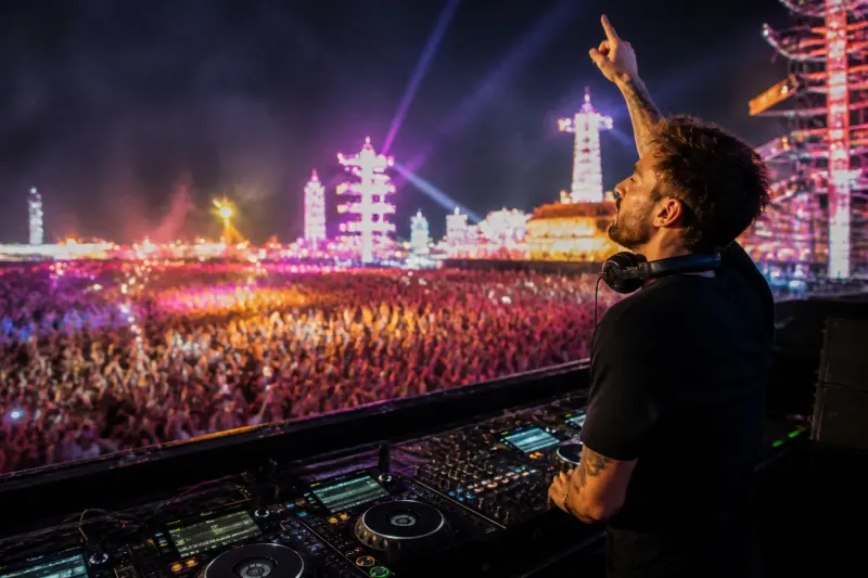 A vibrant dance music venue featuring a DJ and audience enjoying live music.