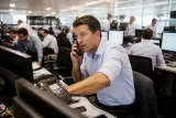 Traders collaborate in a bustling trading floor during a Bitcoin futures spike.