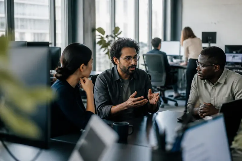 A busy office with individuals discussing the recent DseWiki hijack incident.