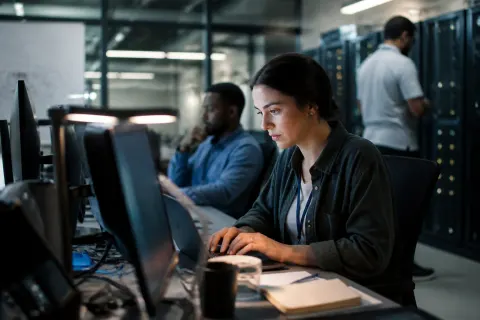 Technicians investigating security protocols in a server room after identifying the vulnerability.