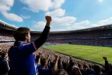 Football fans experiencing a live match in a crowded stadium.