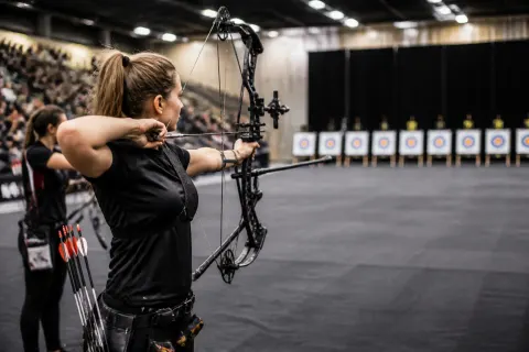 Compound archery event showcasing athletes aiming in a competitive indoor setting.