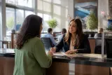 A bank teller assisting a customer in a brightly lit bank branch.