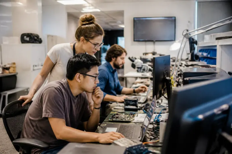 Security researchers discussing ASLR bypass techniques in a tech lab.
