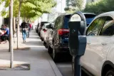 A busy street parking area in the UK with various cars parked and a parking meter in focus.